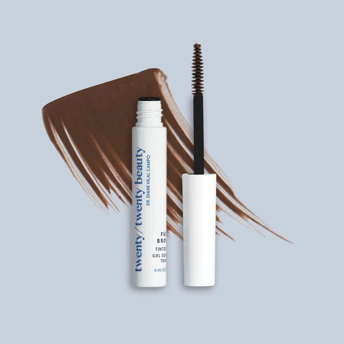 A tube of Twenty Twenty Full Brows Tinted Gel for Fuller Eyebrows, known for enhancing eyebrow fullness, sits with its applicator open on a light gray background. Brown brush strokes behind highlight the products vegan and cruelty-free color.
