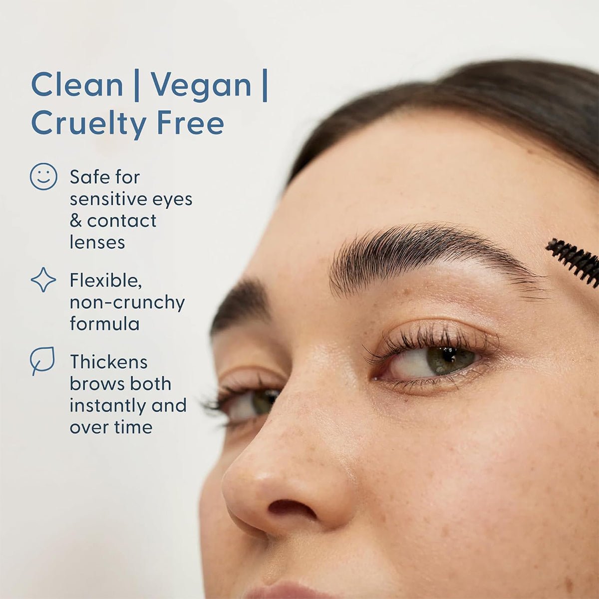 Close-up of a person using Twenty Twenty Full Brows Tinted Gel, showcasing its brush for fuller eyebrows. The text highlights the clean, vegan, and cruelty-free formula ideal for sensitive eyes; this flexible, non-crunchy gel enhances brows effortlessly.
