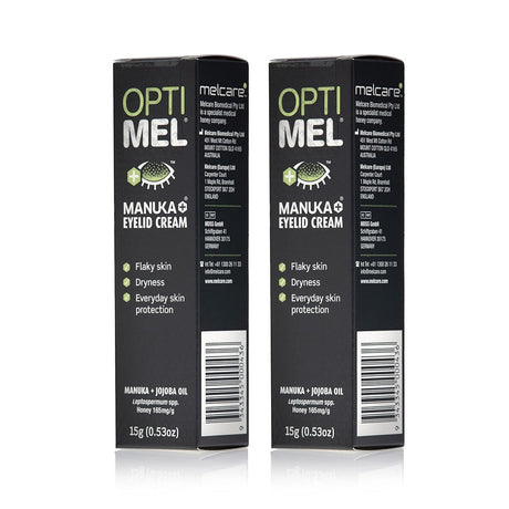 Two tubes of Melcares Optimel Manuka Eyelid Cream for Dry Flaky Skin, each 15g, are depicted. The dark packaging emphasizes its suitability for sensitive skin and highlights benefits like treating dryness and flakiness with a potent blend of Manuka honey and Jojoba Oil.