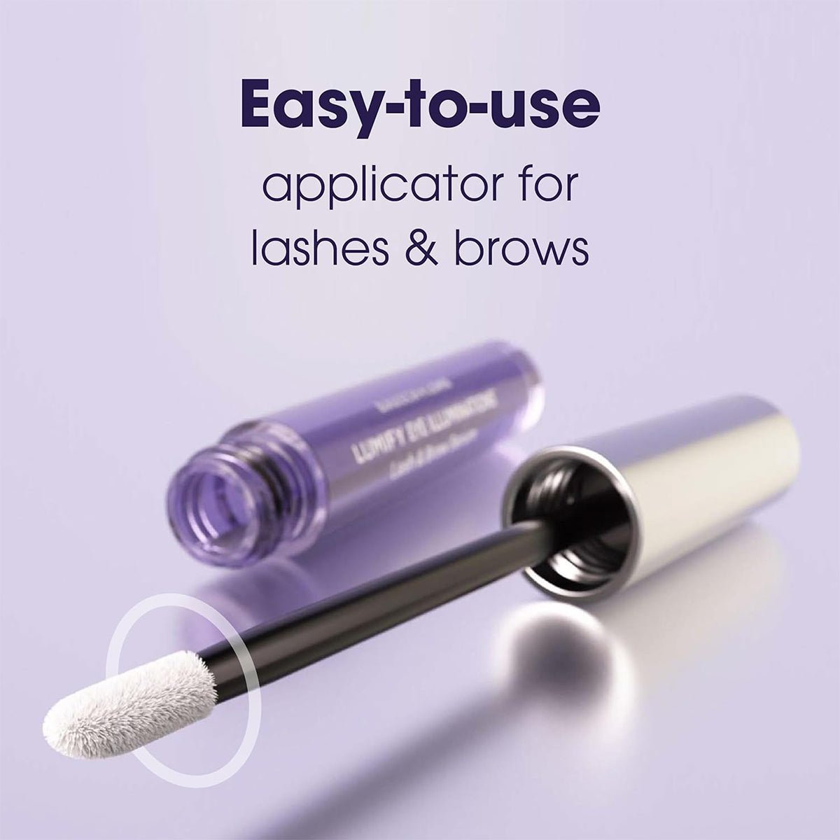 A close-up of a white-tip applicator for Bausch + Lombs LUMIFY Eye Illumination Nourishing Lash & Brow Serum, next to its metallic tube on a purple surface, with text: Effortless Lash & Brow Serum for enhanced fullness.