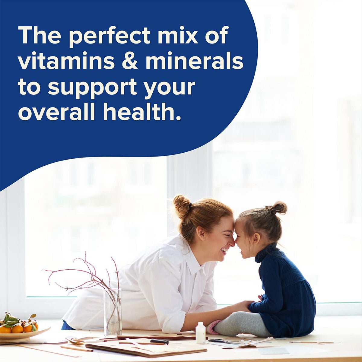 A woman and young girl, smiling warmly, touch foreheads in a bright room. In the background, a window and desk with various items are visible. Text reads: Focus Vitamins Multivitamin Gummies - the perfect mix of vitamins & minerals to support your overall health. (90 Ct, 45 Day Supply).