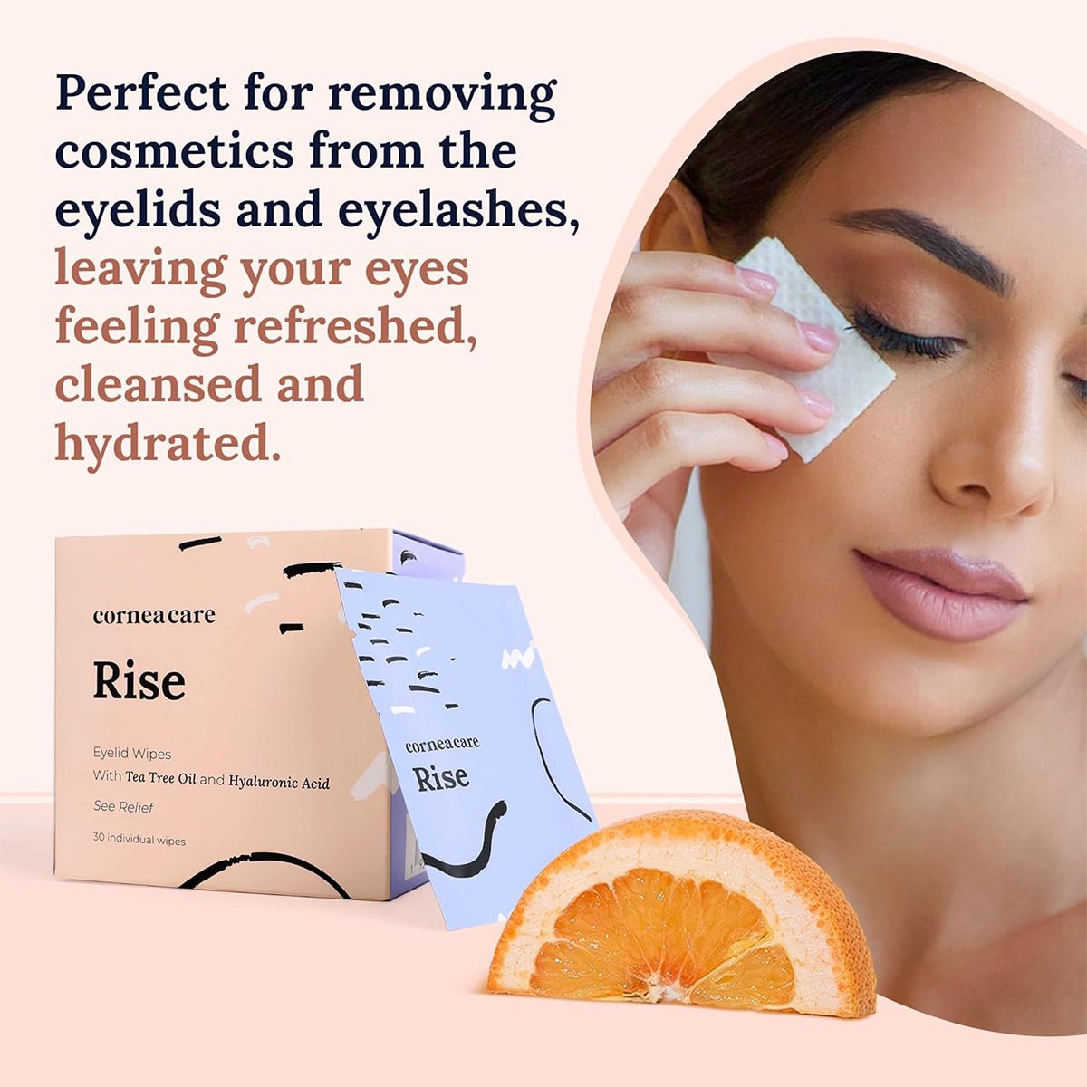 A woman gently wipes her eye with a pad. A box and pouch labeled CorneaCare Wipes with Tea Tree Oil (30ct) lie beside her, accompanied by an orange slice. The text highlights the product as refreshing, hydrating, and ideal for eyelid hygiene and removing eye cosmetics.