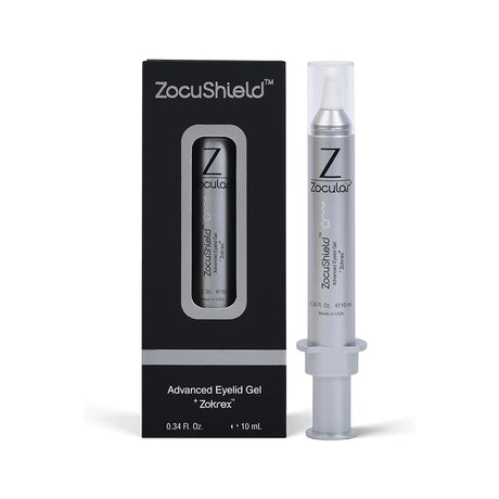 The image shows ZocuShield Gel Eyelid Cleanser by Zocular, with an okra-based complex for dry eye relief. Inside a black box with a window is a sleek silver syringe-like container, capped clear and elegantly labeled with the product name.