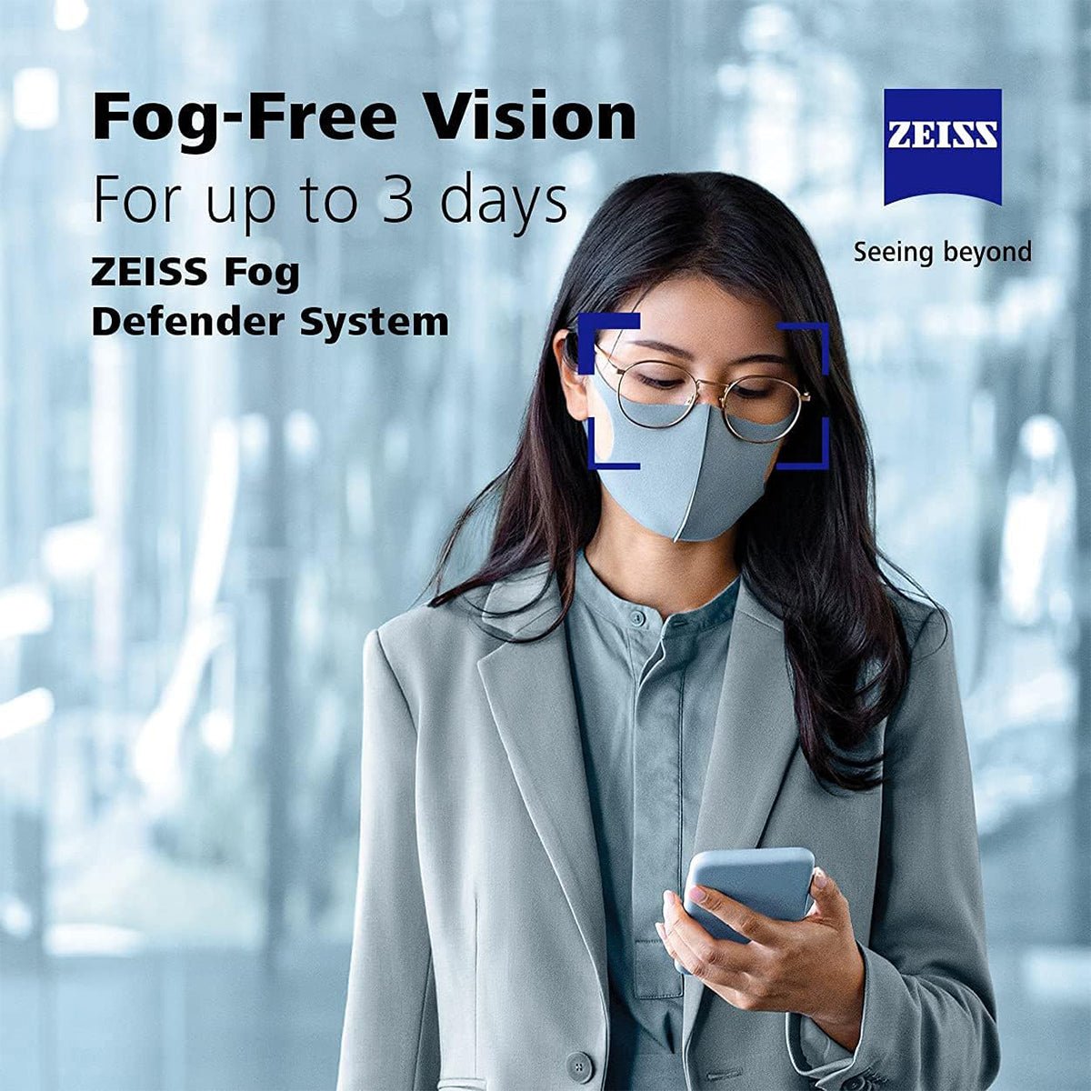 A person in a suit jacket wearing glasses and a mask looks at a smartphone against a blurred background. The text reads: Fog-Free Vision for up to 3 days with ZEISS Fog Defender System Anti-Fog Spray for Glasses. Enjoy clear vision thanks to Zeiss advanced lens cleaning technology.