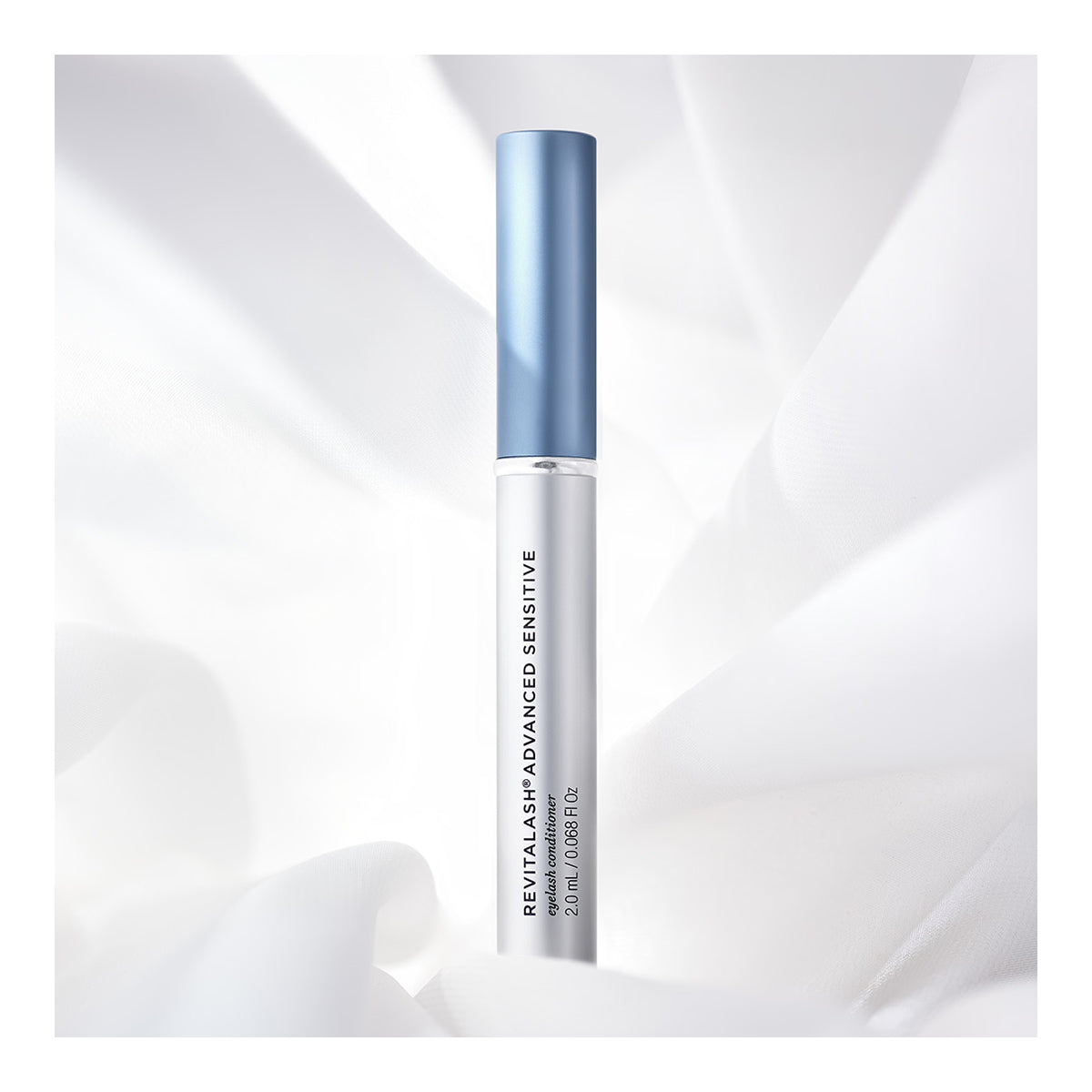 A sleek tube of RevitaLash Advanced Eyelash Conditioner and Enhancing Serum Sensitive (2.0mL, 3 Mo. Supply) rests against a soft white fabric, showcasing its commitment to lash health with a clean, elegant design.