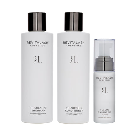 The RevitaLash Volumizing Hair Collection Bundle includes three sleek white bottles: biotin-infused thickening shampoo with a black cap, thickening conditioner with a black cap, and volume enhancing foam with a clear cap.