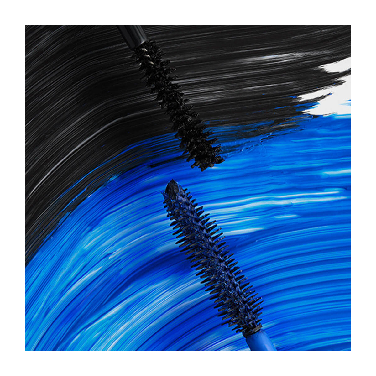 Close-up of two mascara brushes, a Volumizing Mascara and RevitaLashs Double-Ended 2-in-1 Lash Primer & Mascara Volume Set, creating bold strokes on white. The top brush makes a black streak; the bottom creates a vibrant blue streak, showcasing the contrast between the colors.