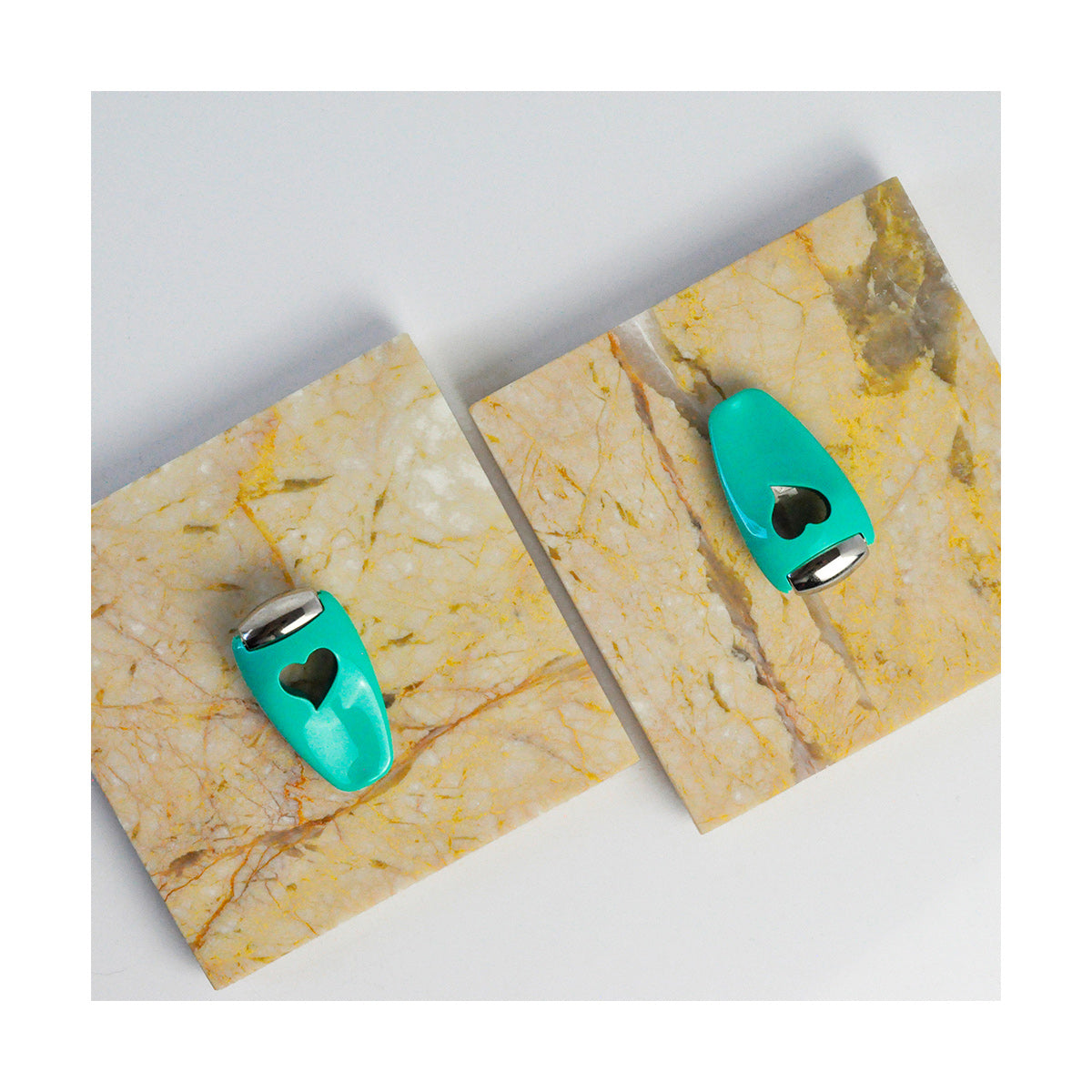 The We Love Eyes Focused Eye Roll, designed for toning, de-puffing, and relaxing tired eyes with fingertip precision, rests on square marble tiles showcasing a speckled pattern of beige and yellowish veins. The photo is taken from above.
