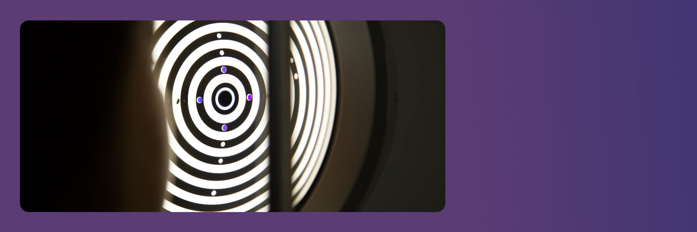 Concentric circular patterns with alternating black and white rings are illuminated, creating a target-like appearance set against a dark backdrop.