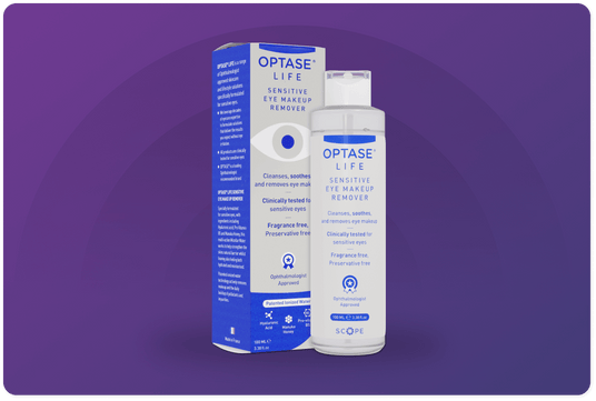 Optase Life Sensitive Eye Makeup Remover bottle next to its purple and white packaging box on a gradient purple background. The product claims to cleanse and soothe delicate eyes, is fragrance-free, and is ophthalmologically approved.