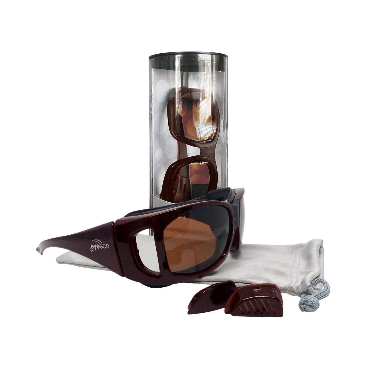 EyeEco Large Moisture Release Eyewear from PRN, featuring Demi Amber with Copper Lens, is showcased. One pair is nestled in a transparent cylindrical case, and another rests atop a white microfiber bag. Nearby accessories enhance the display, emphasizing their practicality.