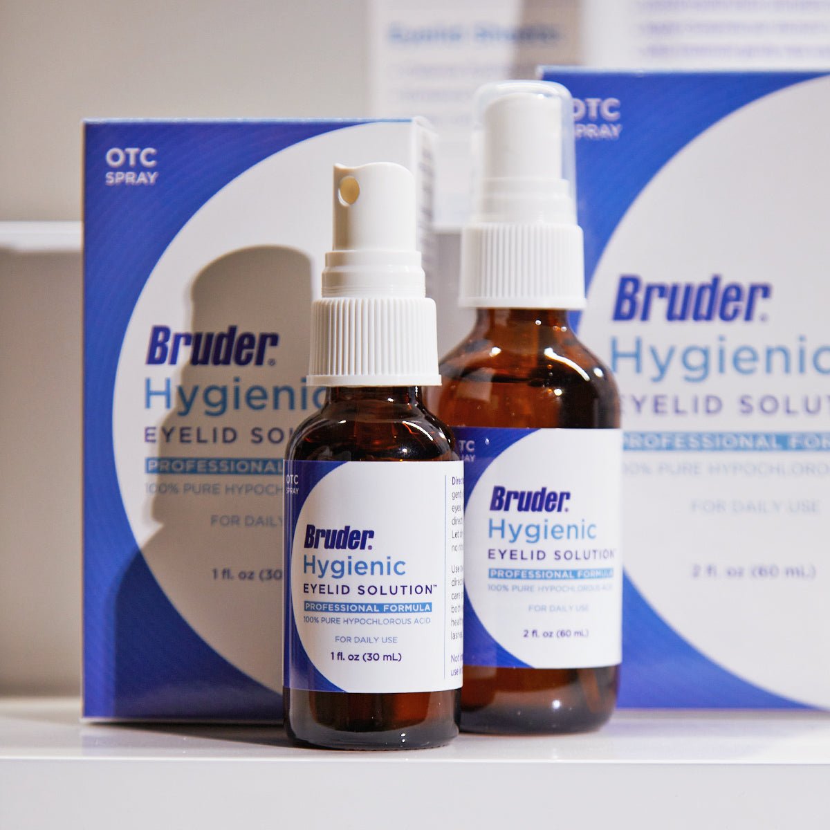 Two brown bottles of Bruder Hypochlorous Hygienic Eyelid Solution (1oz & 2oz) with white spray tops are in front of their boxes, labeled OTC Spray and Professional Formula. With hypochlorous acid, it effectively relieves various eyelid conditions, highlighted by the branding and packaging.