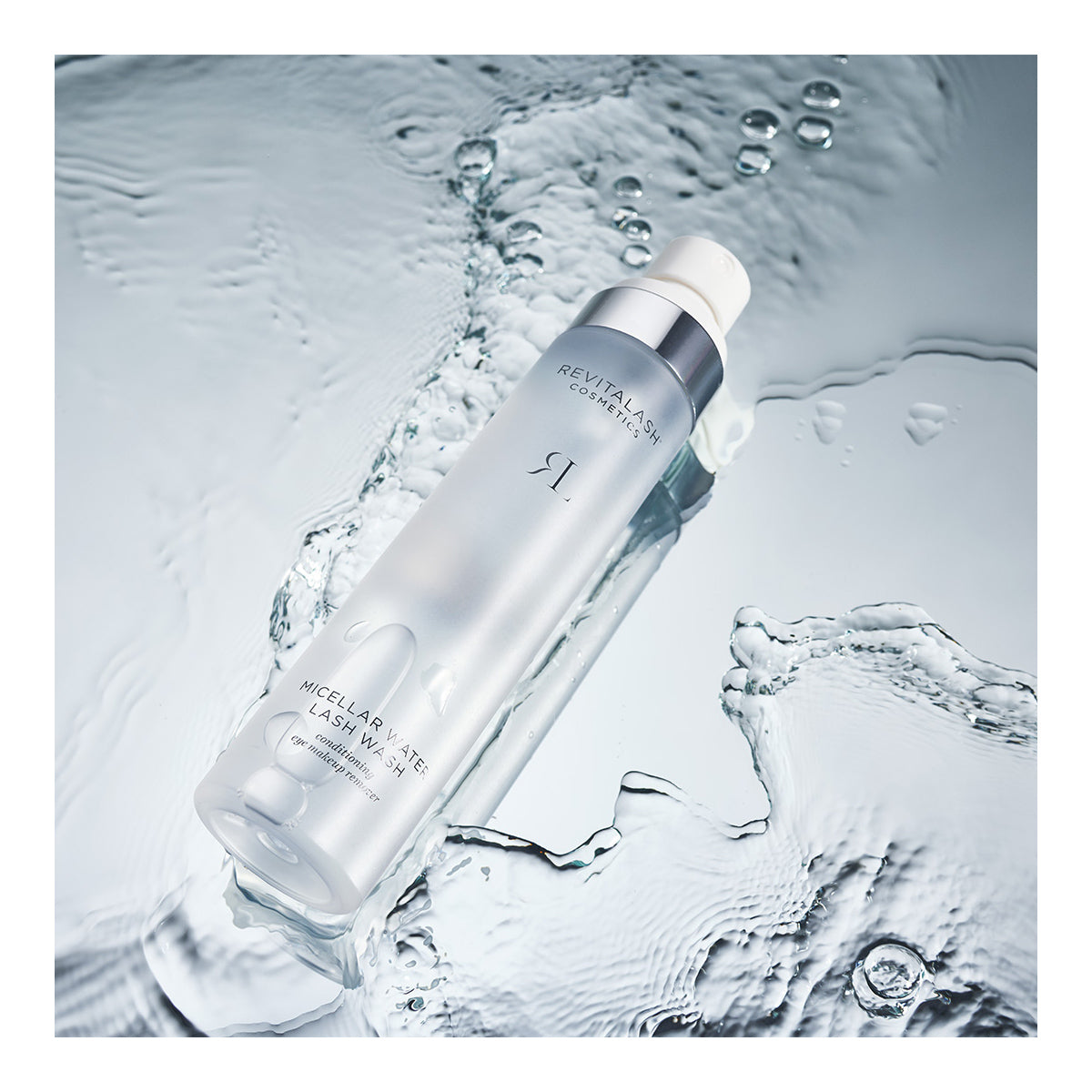 A cylindrical bottle of RevitaLash Micellar Water Lash Wash, Hypoallergenic Makeup Remover (100mL), sits partly submerged on rippling water, creating a serene aesthetic ideal for conditioning makeup removal and gentle on sensitive eyes.