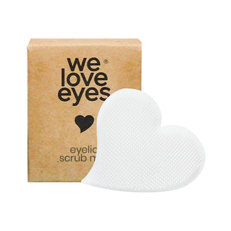 The We Love Eyes Eyelid Scrub Mitt features a heart-shaped scrub made of textured, translucent material, paired with a charming cardboard box adorned with we love eyes text and a heart symbol—a perfect cleanser for gentle care with an adorable touch.