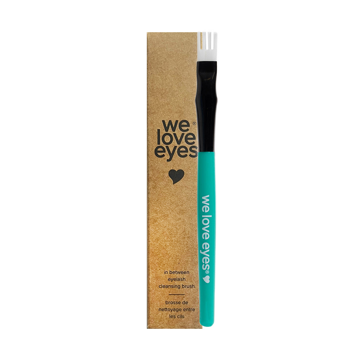 A teal and black fork-shaped eyelash cleansing brush from We Love Eyes is perfect for debris removal, paired with brown heart-themed packaging featuring We Love Eyes In Between Eyelash Cleansing Brush in English and French.