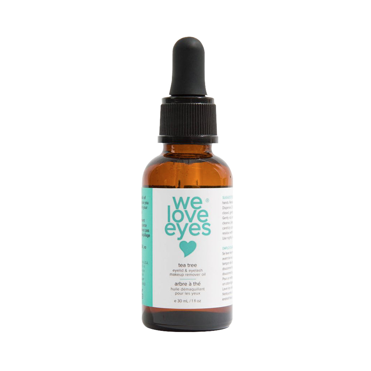 A simple, eco-friendly cardboard box says we love eyes, with a heart below. It reads tea tree eyelid & eyelash makeup remover oil in English and French, featuring organic jojoba oil. Contains 30 mL or 1 fl oz. Brand: We Love Eyes - Remove waterproof makeup easily.